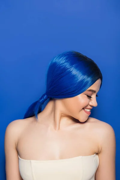 Glowing skin concept, portrait of joyous young woman with vibrant hair color posing with bare shoulders on bright blue background, youth, individualism, beauty trends, unique identity — Stock Photo