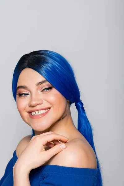 Beauty trends, dyed hair, portrait of tattooed and cheerful woman with bare shoulders posing in bright blouse on grey background, blue hair color, hairstyle, female model, makeup and beauty — Stock Photo