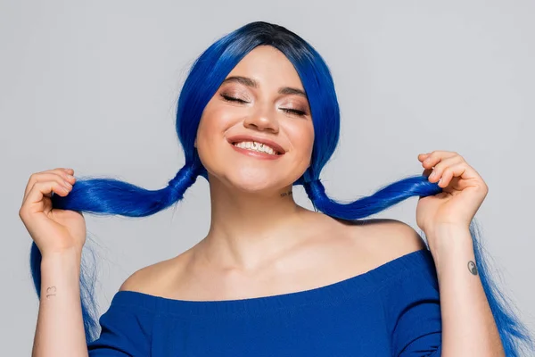 Positivity and youth, tattooed woman with closed eyes and dyed hair smiling on grey background, hairstyle, blue hair, modern beauty, self expression, individualism — Stock Photo
