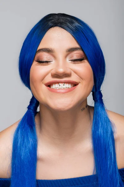 Positividade e juventude, mulher tatuada com olhos fechados e cabelo azul sorrindo no fundo cinza, penteado, cor vibrante, beleza moderna, auto-expressão, individualismo — Fotografia de Stock