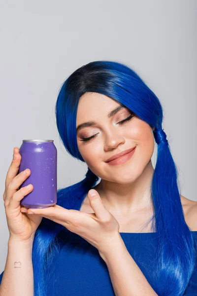 Concepto de verano, mujer joven satisfecha con pelo azul que sostiene la lata de refresco sobre fondo gris, individualismo, juventud y estilo de vida, color vibrante, auto expresión, identidad única, subcultura moderna - foto de stock
