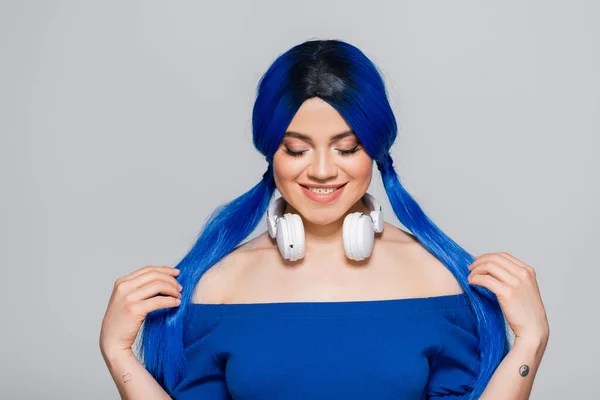 Musikliebhaberin, glückliche junge Frau mit blauen Haaren und kabellosen Kopfhörern, die auf grauem Hintergrund lächeln, lebendige Jugend, Individualismus, moderne Subkultur, Selbstausdruck, Tätowierung, Sound — Stockfoto