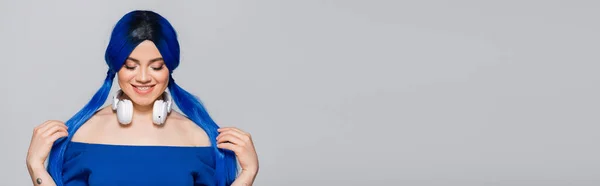 Musikliebhaberin, glückliche junge Frau mit blauen Haaren und kabellosen Kopfhörern, die auf grauem Hintergrund lächelt, lebendige Jugend, Individualismus, moderne Subkultur, Selbstausdruck, Tätowierung, Sound, Banner — Stock Photo