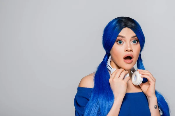 Musikliebhaberin, staunende junge Frau mit blauen Haaren und kabellosen Kopfhörern, die auf grauem Hintergrund lächelt, lebendige Jugend, Individualismus, moderne Subkultur, Selbstausdruck, Tätowierung, Sound — Stockfoto