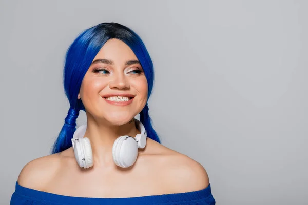 Musikliebhaberin, lächelnde junge Frau mit blauen Haaren und kabellosen Kopfhörern, die auf grauem Hintergrund lächelt, lebendige Jugend, Individualismus, moderne Subkultur, Selbstausdruck, Tätowierung, Sound — Stockfoto