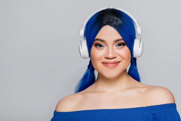 Music lover, smiling young woman with blue hair listening music in wireless headphones on grey background, vibrant youth, individualism, modern subculture, self expression, tattoo, sound — Stock Photo
