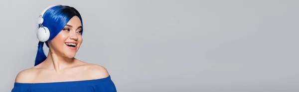Selbstausdruck, fröhliche junge Frau mit blauen Haaren, die Musik in drahtlosen Kopfhörern auf grauem Hintergrund hört, lebendige Jugend, Individualismus, moderne Subkultur, Tätowierung, Sound, Banner — Stockfoto
