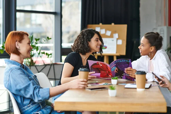 Rousse femme avec café pour aller regarder gai afro-américaine et multiraciale copines lecture magazine et avoir du plaisir dans les femmes club, intérêts communs et concept de partage de connaissances — Photo de stock