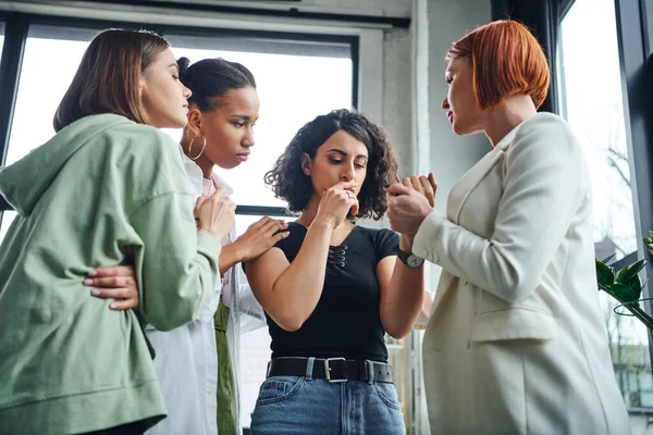 Psychologist holding hand of frustrated multiracial woman and calming her together with multiethnic friends during motivation session in consulting room, problem-solving and mutual support concept — Stock Photo