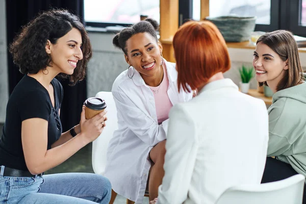Femme multiraciale assis avec café pour aller écouter psychologue rousse avec des copines multiethniques optimistes pendant la thérapie, la compréhension, le soutien et la santé mentale concept — Photo de stock