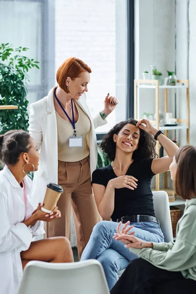 Delighted multiracial woman smiling with closed eyes near motivation coach and multiethnic friends sitting in consulting room, understanding, support and mental health concept — Stock Photo