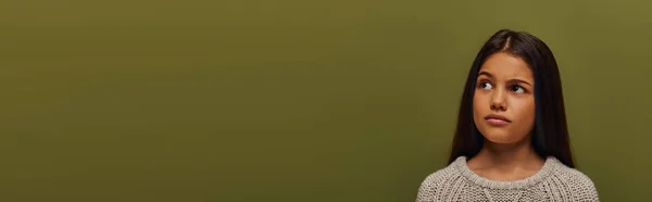 Retrato de menina morena pré-adolescente pensativa em camisola de malha na moda olhando para longe enquanto estava isolada no verde com espaço de cópia, menina elegante no conceito de traje de queda acolhedor, banner — Fotografia de Stock