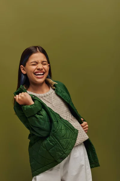 Excited and stylish preadolescent girl with dyed hair showing yes gesture while posing in autumn jacket and knitted sweater isolated on green, modern fall fashion for preteens concept — Stock Photo