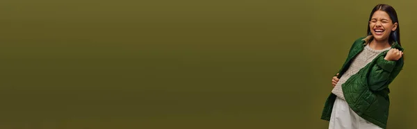 Menina pré-adolescente animado com cabelo tingido mostrando sim gesto enquanto posando em jaqueta e suéter de malha, enquanto em pé isolado em verde, moda outono moderno para conceito pré-adolescentes, banner — Fotografia de Stock