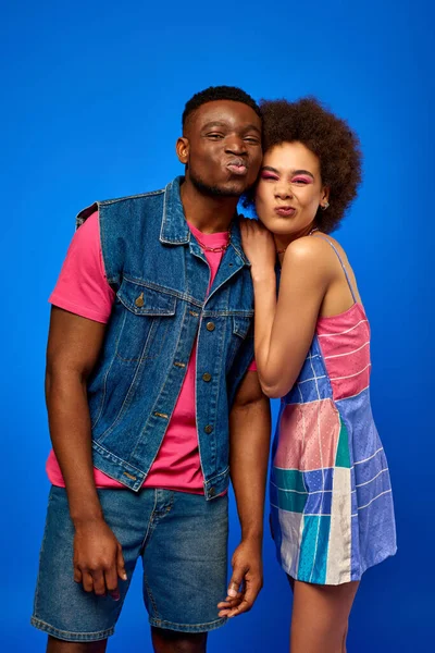 Jovem afro-americano melhores amigos na moda verão roupas brilhantes rimando enquanto estão juntos e olhando para a câmera isolada em azul, melhores amigos em roupas combinando, amizade — Fotografia de Stock
