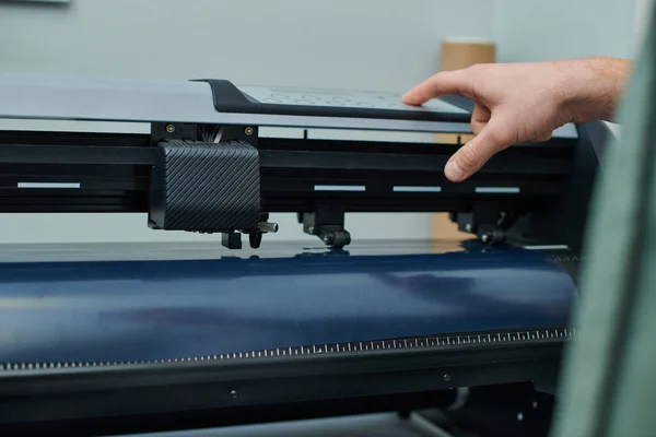 Zugeschnittene Ansicht junger Handwerker mit Siebdruckmaschine während des Prozesses im Druckstudio, Kleinunternehmer, der an Projekt, Druckgrafik, kreativem Prozess, Workflow arbeitet — Stockfoto