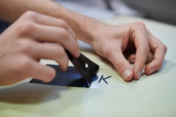 Ausgeschnittene Ansicht junger Handwerker, die Schicht für Siebdruck herstellen, während sie im Druckstudio arbeiten, Kleinunternehmer, die an einem Projekt arbeiten, Nahaufnahme, kreativer Prozess, Workflow — Stockfoto