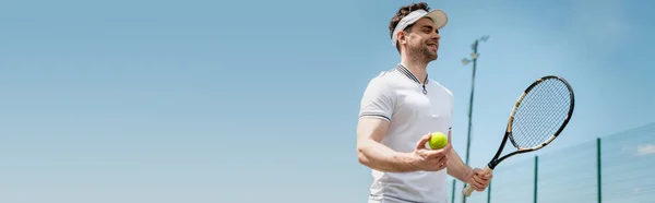 Bannière, joueur de tennis joyeux dans la casquette de visière tenant raquette et ballon sur le court, fitness et motivation — Photo de stock