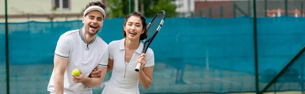 Баннер, веселая пара в активной одежде держа ракетки и мяч возле теннисной сети, хобби и спорта — стоковое фото