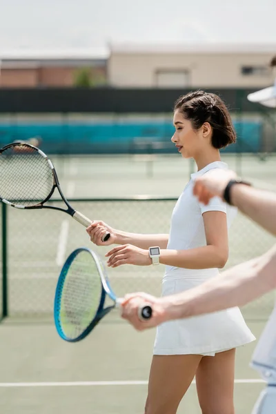 Femme en jupe de tennis pratiquant sur le court de tennis, tenant raquette, petit ami et petite amie, sport — Photo de stock