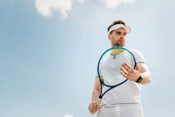 Здоровый образ жизни, красивый мужчина в активной одежде и козырьковой шапке проведение теннисной ракетки на корте — стоковое фото