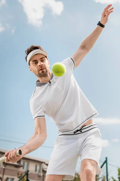 Balle de tennis floue au premier plan, beau joueur de tennis jouant sur le court, la motivation et le sport — Photo de stock