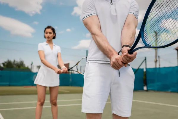 Спортивный человек проведение теннисной ракетки рядом с подругой на корте, пара спорт, мотивация, хобби — стоковое фото