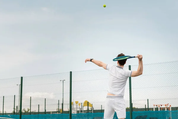 Спина, человек в активной одежде играет в теннис, держа рейки, ударяя мячом, спина, вид сзади — стоковое фото