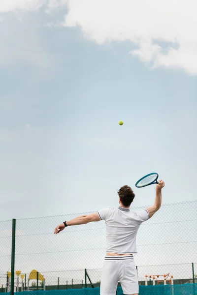 Vista trasera del hombre jugando al tenis en la cancha, sosteniendo la raqueta, golpeando la pelota, revés - foto de stock