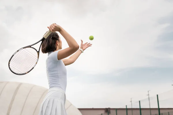 Вид сзади женщины, ударяющей по мячу во время игры в теннис на корте, мотивация и спорт — стоковое фото