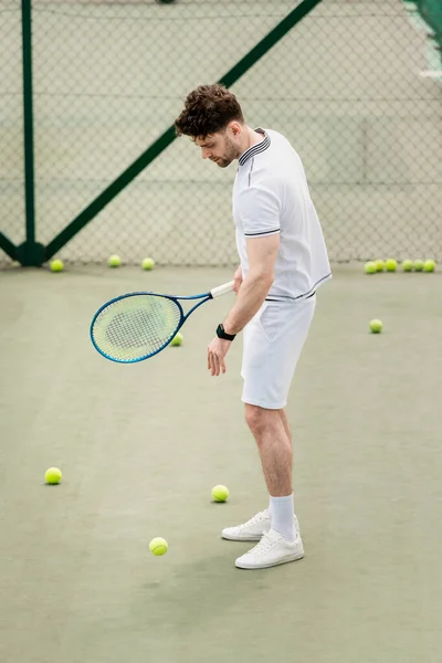 Теннисные мячи вокруг спортсмена с ракеткой на корте, хобби и отдых, красивый игрок — стоковое фото