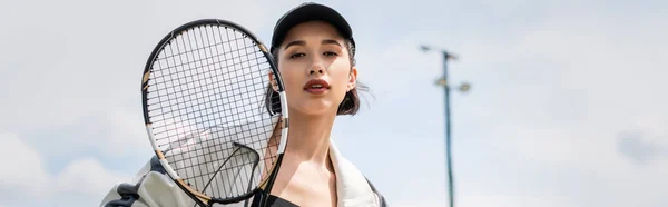 Pancarta, mujer en desgaste activo y gorra mirando a la cámara y la celebración de raqueta de tenis en la cancha, deporte - foto de stock