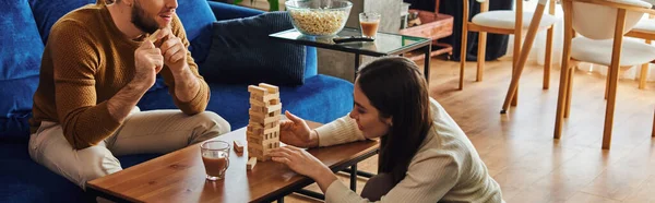 Woman playing wood blocks game with boyfriend near popcorn and coffee at home,banner — Stock Photo