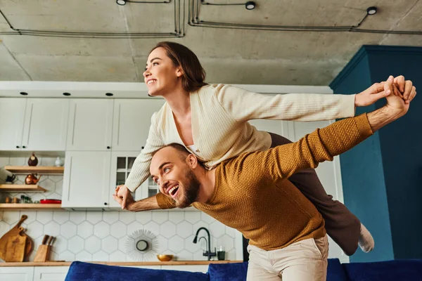 Smiling couple in casual clothes holding hands and having fun together in living room — Stock Photo