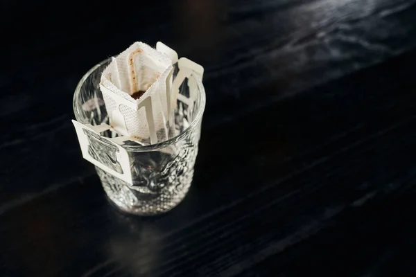 Высокий угол обзора хрусталя с молотым кофе на черном столе, метод пивоварения — стоковое фото