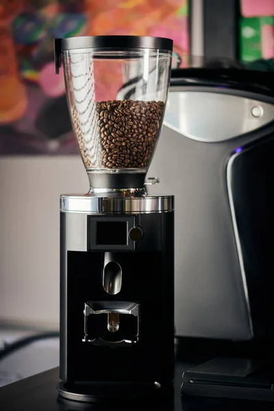 Coffee shop equipment, aromatic, roasted and whole coffee beans in professional electric grinder — Stock Photo