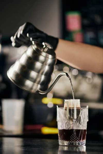 Barista con bollitore sgocciolatoio versando acqua bollente in bicchiere con filtro caffè, pour-over espresso — Foto stock