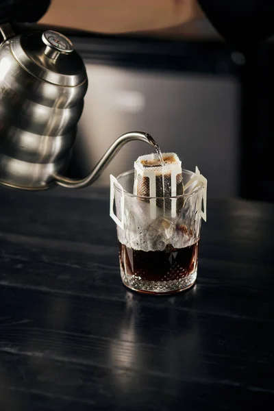 Brebaje alternativo, agua hirviendo vertiendo en vidrio con café en bolsa de filtro, espresso vertido - foto de stock