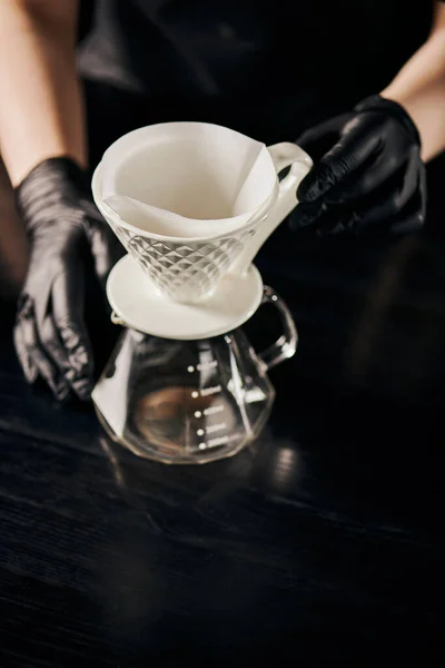 Barista in black latex gloves near ceramic dripper and glass pot, V-60 style espresso brewing method — Stock Photo