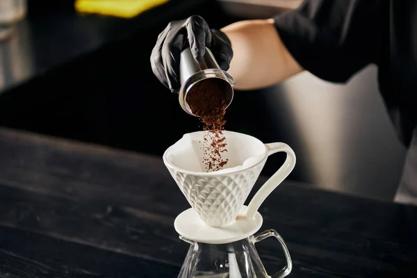 Barista verter café molido fino de jigger en gotero de cerámica, preparando V-60 estilo espresso - foto de stock