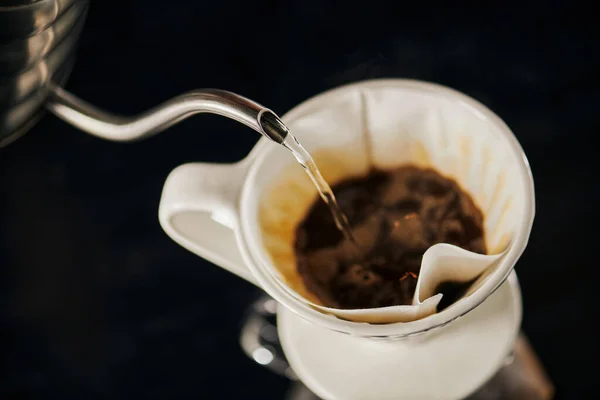V-60 style espresso brewing, boiling water pouring into ceramic dripper with black ground coffee — Stock Photo