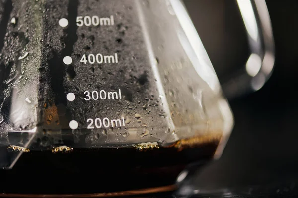 Close up view of black freshly brewed espresso in glass coffee pot with measuring scale, drip method — Stock Photo