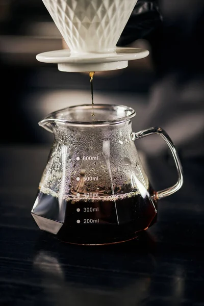 Frisch gebrühter Espresso, der aus dem Keramiktropfer in eine Glaskanne tropft, alternatives Gebräu im V-60-Stil — Stockfoto
