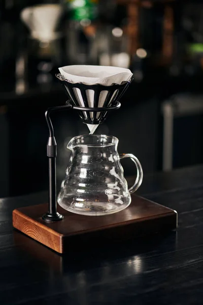 Drip holder with filter bag, glass coffee pot on black wooden counter, alternative V-60 style method — Stock Photo