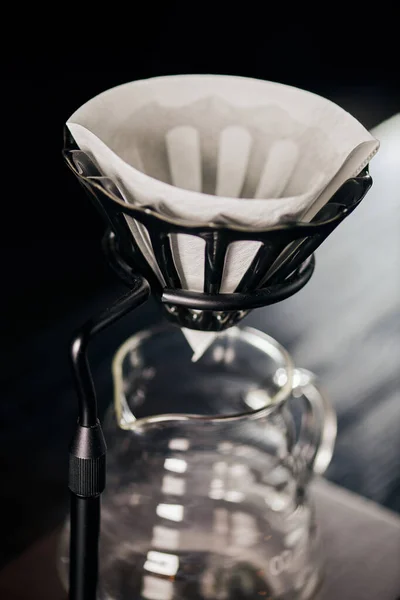 Vista de cerca de la bolsa de filtro de café en el soporte goteado por encima de la cafetera de vidrio, método de elaboración de cerveza estilo V-60 - foto de stock