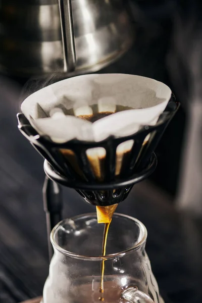 Свежий эспрессо капает в стеклянный кофейник из бумажного фильтра в дриппер стенд, в стиле V-60 — стоковое фото
