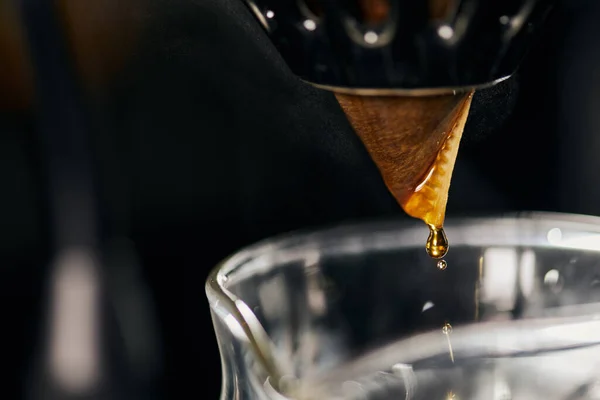 Vista cercana del espresso que gotea del filtro de papel en el soporte del gotero en la olla de cristal, método V-60 - foto de stock