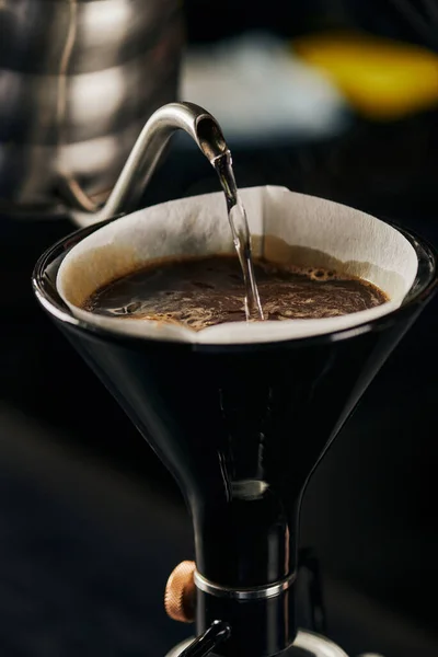 Água fervente que despeja da chaleira na cafeteira do sifão com filtro de papel e café com espuma — Fotografia de Stock
