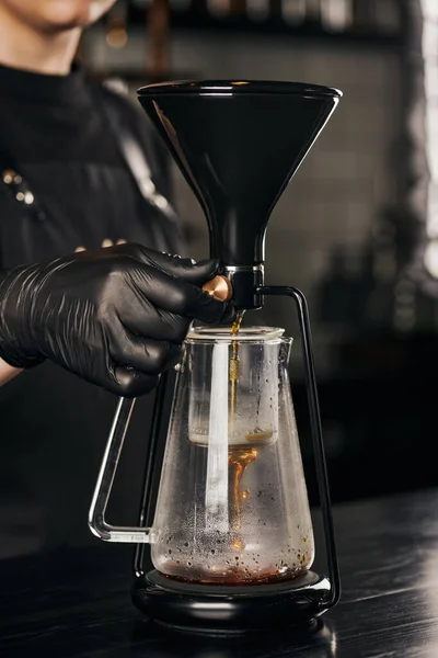 Barista in black latex glove regulating siphon coffee maker while brewing natural pour-over espresso — Stock Photo