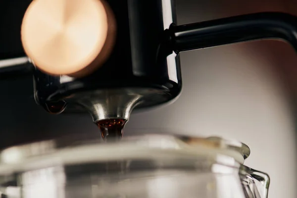 Закрыть вид на свежеваренный эспрессо капает из сифона кофеварка, размытый передний план — стоковое фото